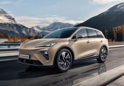 Tan electric MGS6 EV driving on a mountain road.